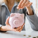 Savings for crisis. Woman puts money in piggy bank.