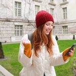 Portrait of cheerful redhead woman with smartphone, celebrating, reading amazing news and rejoicing