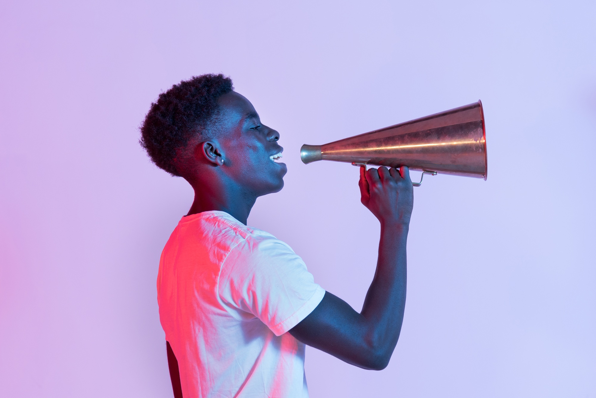 Positive young African American man with vintage megaphone in studio